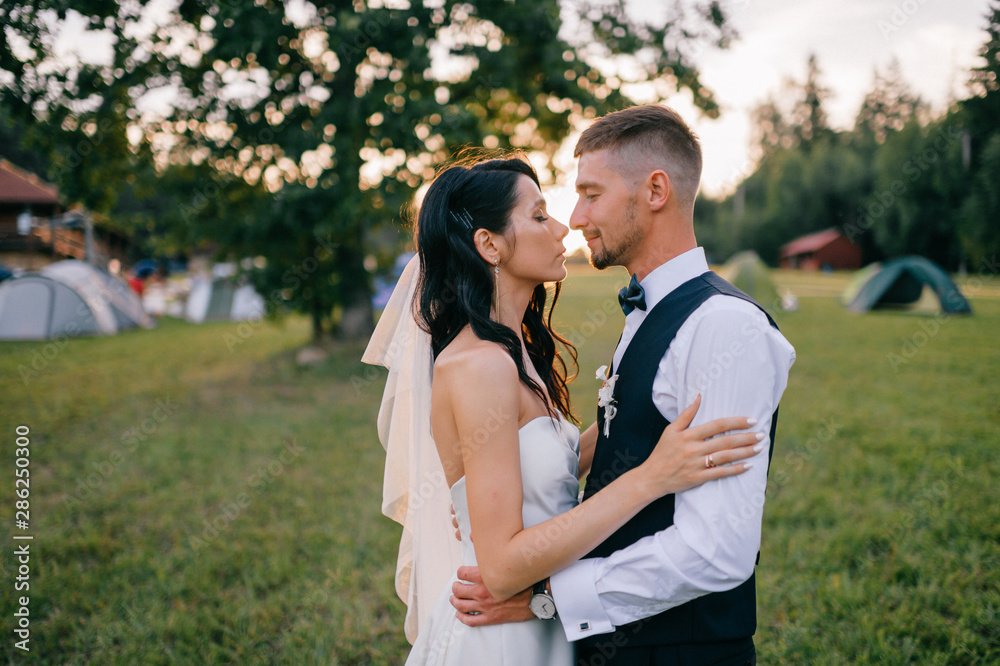 Beautiful wedding couple hugging outdoor at sunset Beautiful wedding couple hugging outdoor at sunset