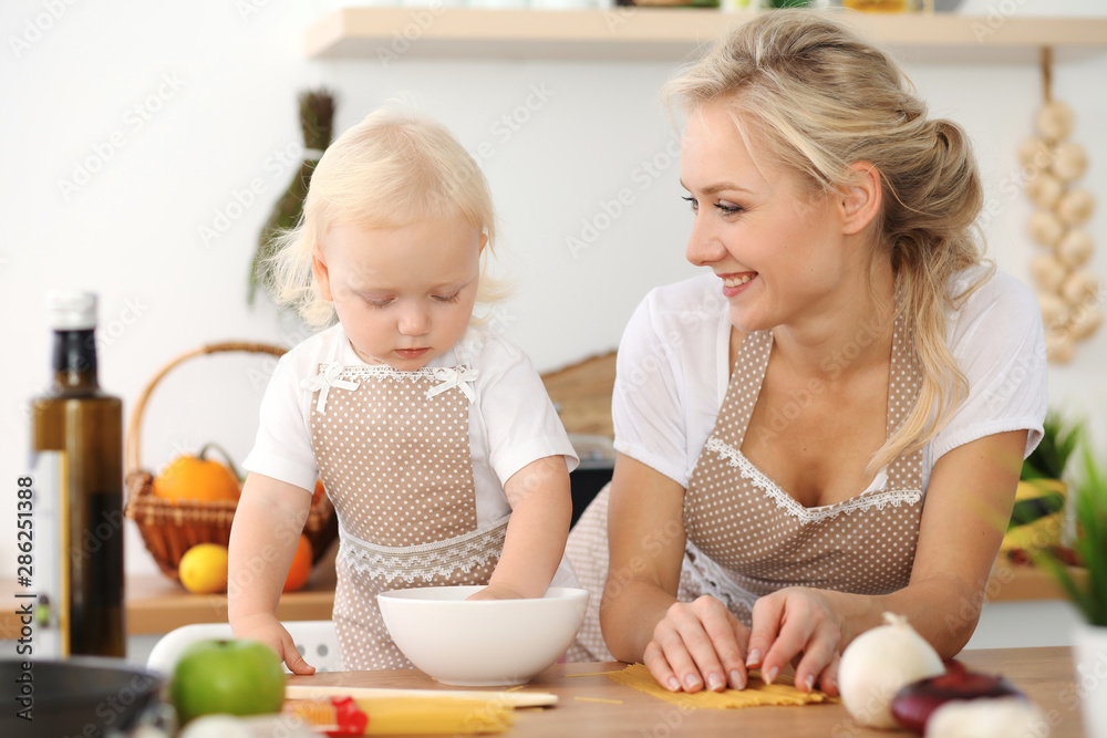 Happy mother and little daughter cooking in kitchen. Spending time all together, family fun concept Happy mother and little daughter cooking in kitchen. Spending time all together, family fun concept