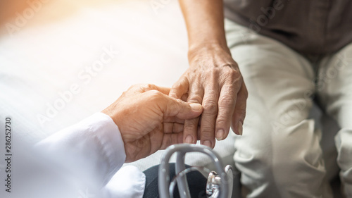 Parkinson's disease patient, Arthritis hand pain or mental health care concept with geriatric doctor consulting examining elderly senior aged adult in medical exam clinic or hospital photo