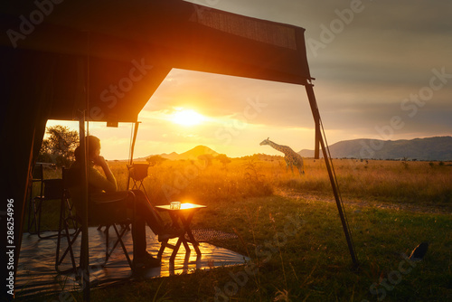 Woman rests after safari in luxury tent during sunset camping in African savannah of Serengeti National Park,Tanzania. photo