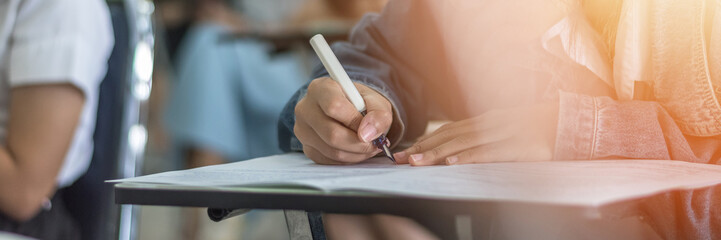 Exam at school with student's taking educational admission test in class, thinking hard, writing answer in university classroom, education and world literacy day concept