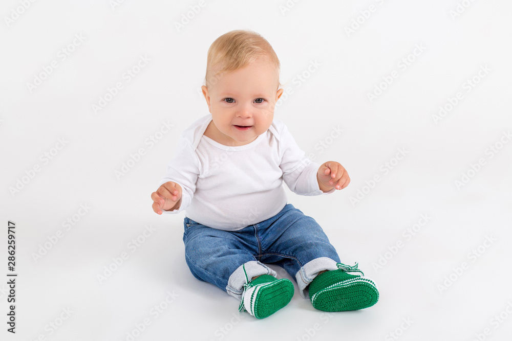 Cute kid sitting on the floor on the white background Cute kid sitting on the floor on the white background