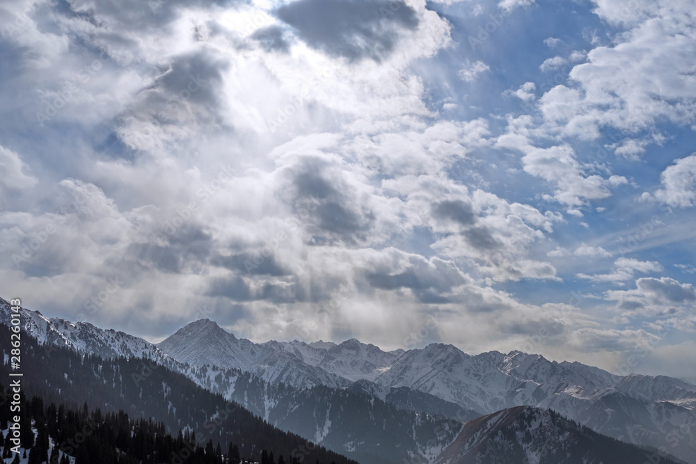 Spectacular condition of the sky with sunbeams over the rocky mountains in the winter season