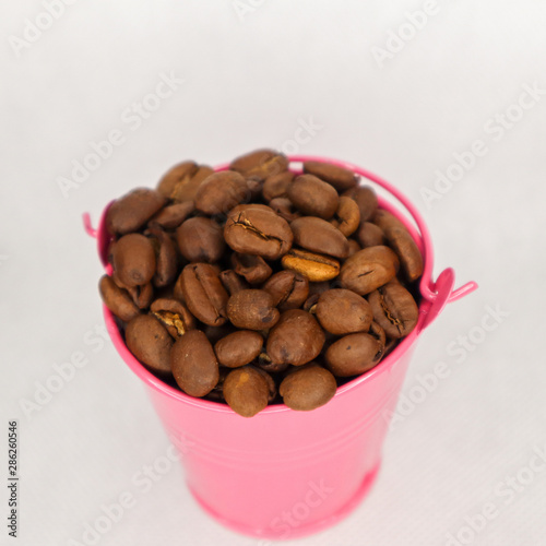 Fototapeta Naklejka Na Ścianę i Meble -  Heap coffee beans in pink bucket on white background