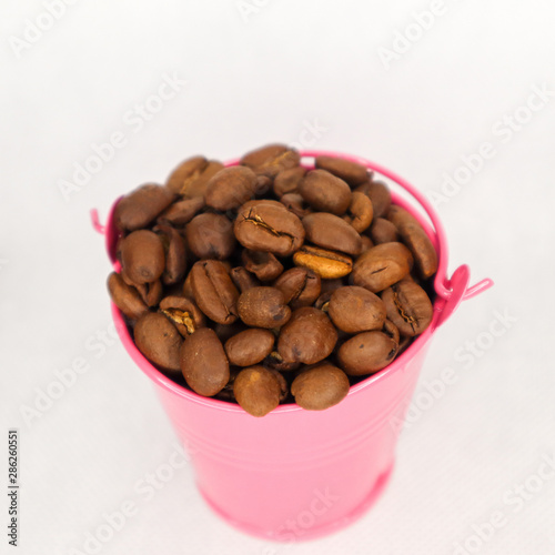 Fototapeta Naklejka Na Ścianę i Meble -  Heap coffee beans in pink bucket on white background