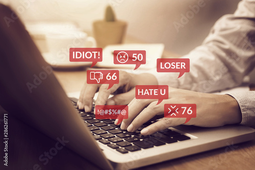 cyber bullying concept. people using notebook computer laptop for social media interactions with notification icons of hate speech and mean comment in social network photo