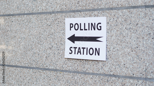 Polling station sign with direction on wall