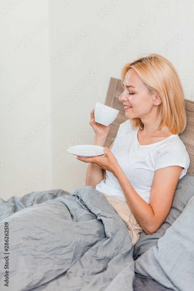 Woman sitting on bed drinking coffee Woman sitting on bed drinking coffee