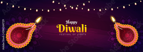 Happy Diwali celebration header or banner design with top view of illuminated oil lamps (Diya) and lighting garland decorated on purple texture background.