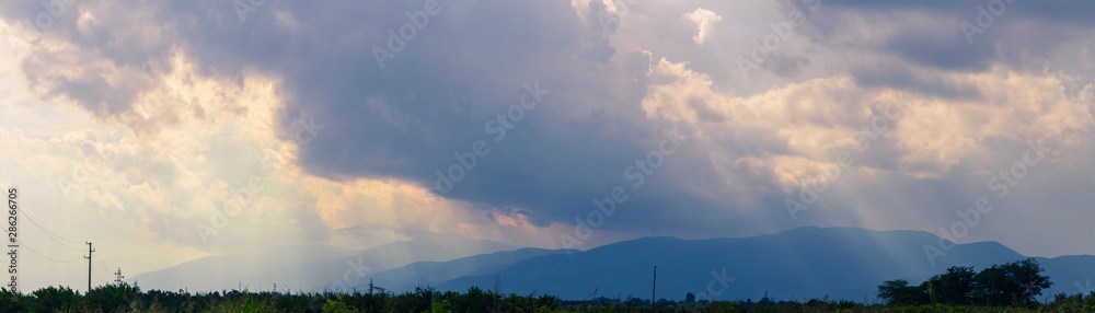 Thunderhead covers the Balkans. Downpour is approaching agricultural land. Villages, fields and forests of Bulgaria before the rain. The terrain in southern Europe. Panorama.