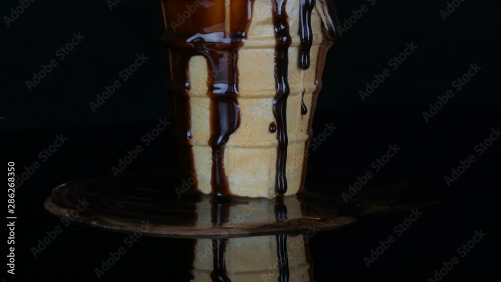Melting ice cream on which pours chocolate syrup sauce on a black background Melting ice cream on which pours chocolate syrup sauce on a black background