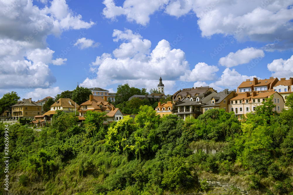 clean old European city with beautiful colorful houses near park natural green natural space on blue sky with white clouds background 