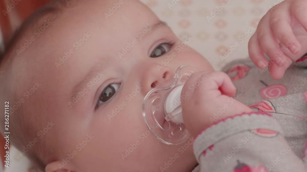 Slow motion shot of little baby girl with beautiful eyes lying in crib Slow motion shot of little baby girl with beautiful eyes lying in crib