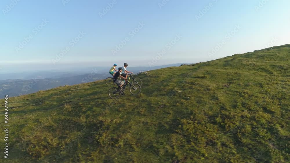 AERIAL: Group of friends pedalling their electric bikes up a grassy hill on a sunny afternoon. Three young mountain bikers climb a grassy mountain during a downhill bike ride session in Slovenia. AERIAL: Group of friends pedalling their electric bikes up a grassy hill on a sunny afternoon. Three young mountain bikers climb a grassy mountain during a downhill bike ride session in Slovenia.