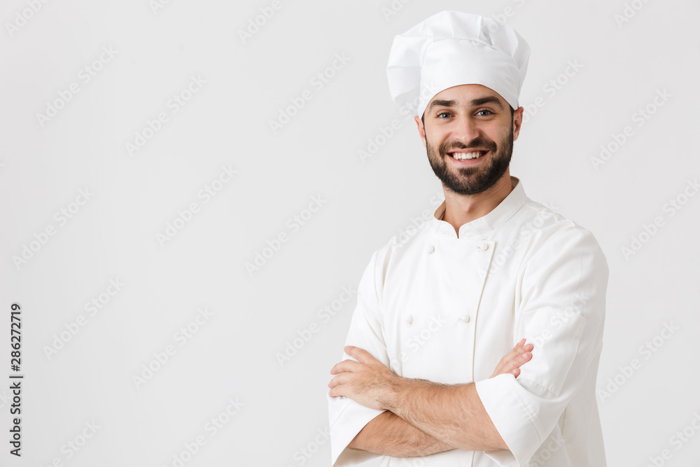 Young chef posing isolated over white wall background in uniform. Young chef posing isolated over white wall background in uniform.