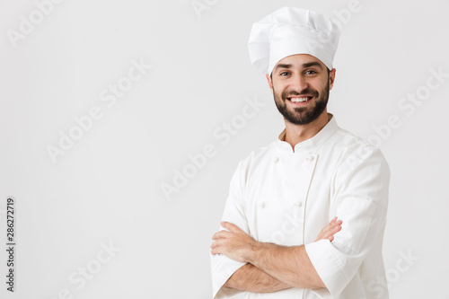 Young chef posing isolated over white wall background in uniform. photo