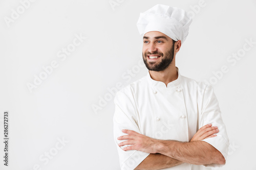Pleased happy young chef posing isolated over white wall background in uniform. photo