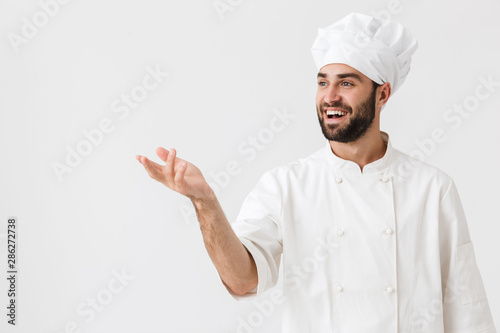 Happy young chef posing isolated over white wall background in uniform.