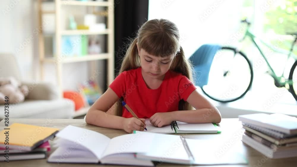 Cute little girl doing homework assignment at table in room Cute little girl doing homework assignment at table in room