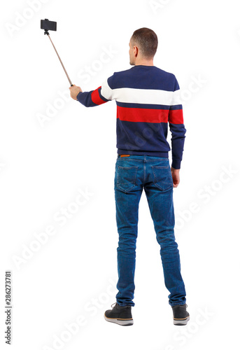 back view of standing young guy with smartphone in the hands of.