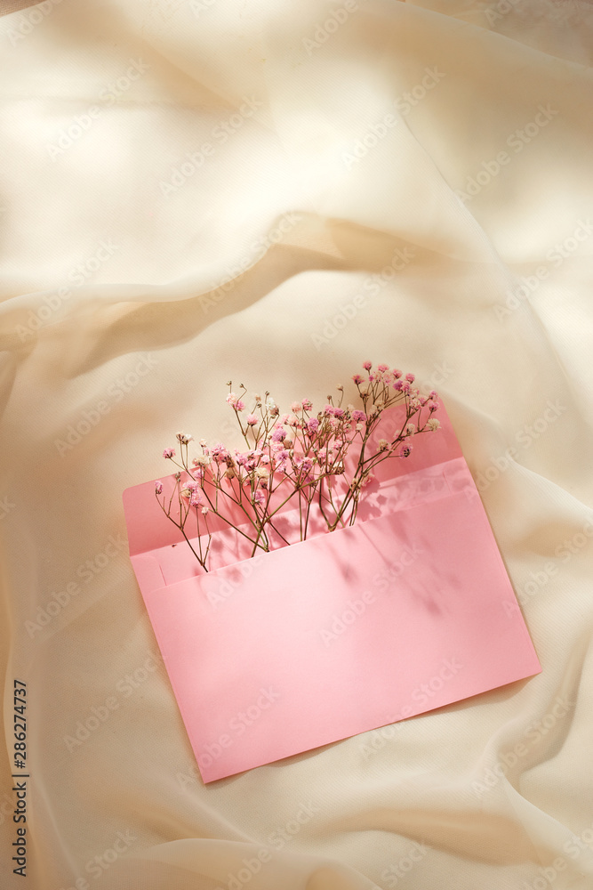 Pink envelope with a spring flower arrangement. Flat lay, top view Pink envelope with a spring flower arrangement. Flat lay, top view