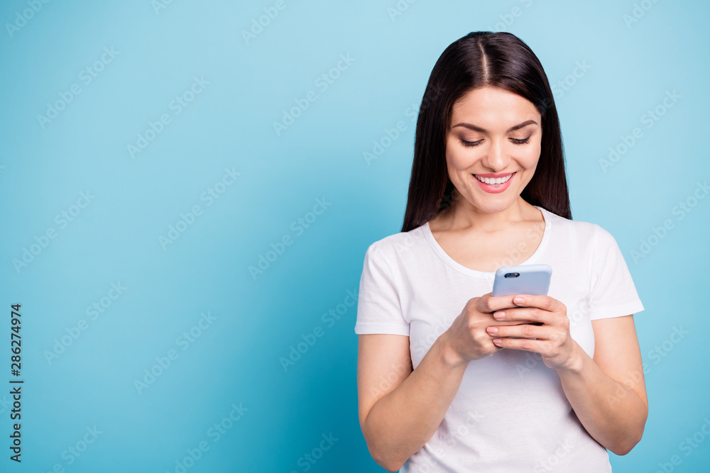 Copyspace photo of cheerful nice cute girlfriend browsing through her telephone while isolated with blue background Copyspace photo of cheerful nice cute girlfriend browsing through her telephone while isolated with blue background