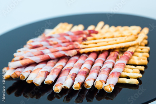 Parma ham prosciutto with grissini breadsticks on cutting board