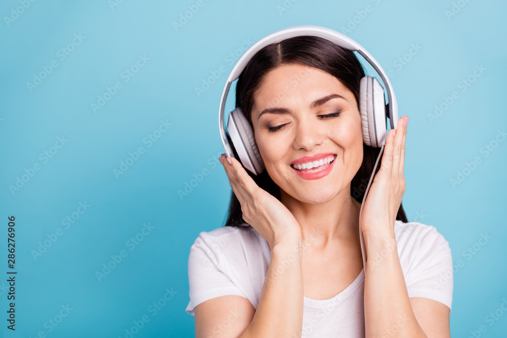 Close up photo of cute charming beautiful girlfriend feeling harmony and rhythm while listening to her beloved musician while isolated with blue background Close up photo of cute charming beautiful girlfriend feeling harmony and rhythm while listening to her beloved musician while isolated with blue background
