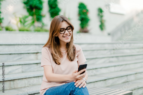 smiling woman uses phone outdoors