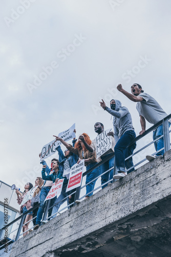 low angle view of multicultural group of people screaming and gesturing while holding placards © LIGHTFIELD STUDIOS