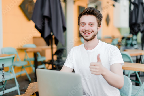 smiling man shows thumbs up while working on laptop
