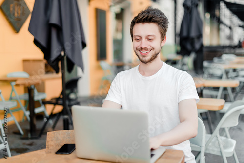 man using laptop for remote work in cafe