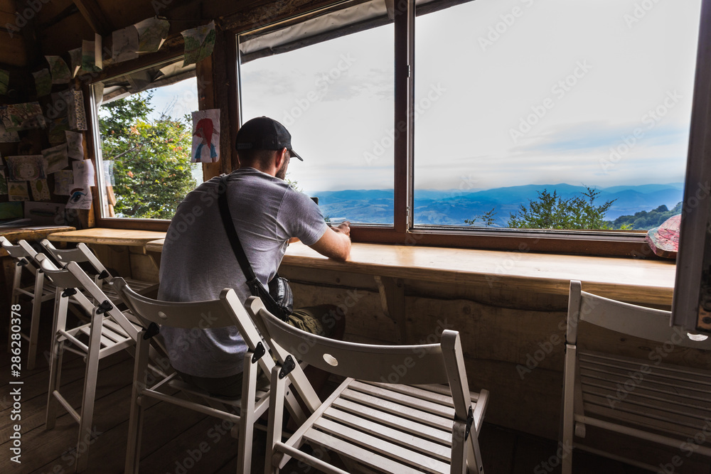 man holding a glass of hot tea overlooking the mountains and sky