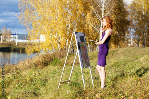Wallpaper Mural Beautiful woman in purple dress painting outdoors in autumn park. Torontodigital.ca