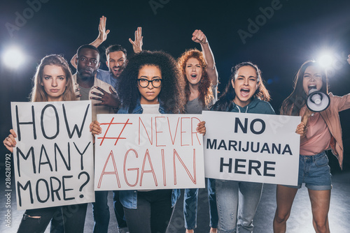 emotional multicultural people screaming while holding placards with lettering on black © LIGHTFIELD STUDIOS