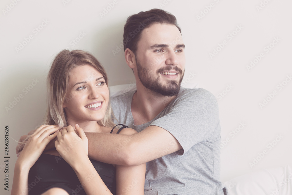 Couple in bed. Young white male and blonde female. Man hugging his wife. Modern couple lifestyle concept. Couple in bed. Young white male and blonde female. Man hugging his wife. Modern couple lifestyle concept.