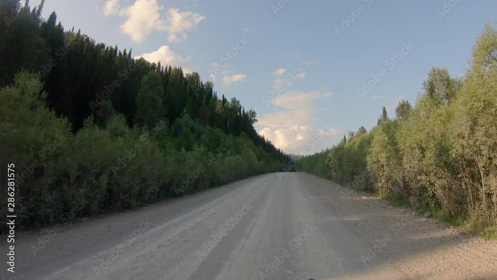 outside view of the car on the road, in a remote taiga among the mountains. riding on a gravel road amid a beautiful forest. summer, dusty road among the mountains and the forest. video footage 4K outside view of the car on the road, in a remote taiga among the mountains. riding on a gravel road amid a beautiful forest. summer, dusty road among the mountains and the forest. video footage 4K