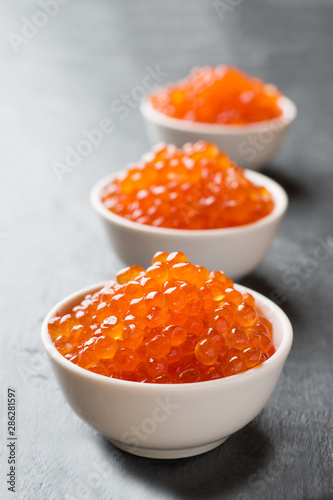 red salmon caviar in a plate on a dark table.
