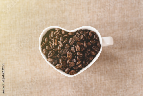 directly above view a heart shape mug of a raw roasted coffee beans. Concept of Favorite drink and coffee addiction
