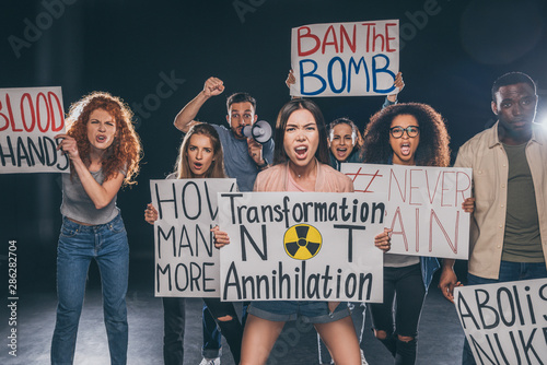 emotional multicultural men and women holding placards with letters and screaming on black © LIGHTFIELD STUDIOS