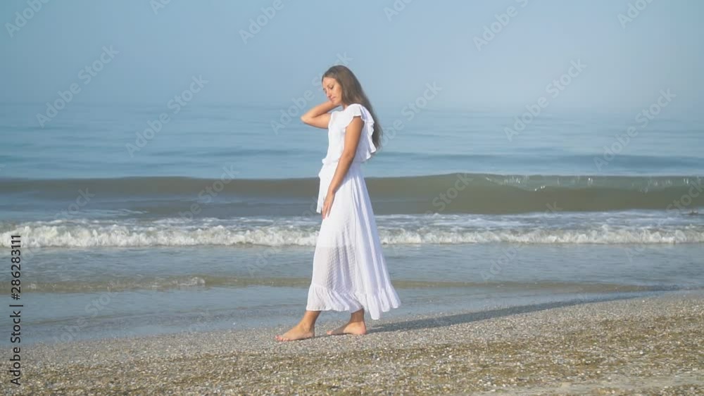 girl in a white dress walks by the sea girl in a white dress walks by the sea