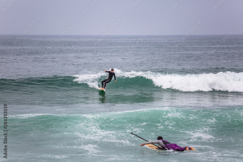 Beach view with professional surfers and Standup Paddleboarding doing extreme maneuvers in sea with waves Beach view with professional surfers and Standup Paddleboarding doing extreme maneuvers in sea with waves