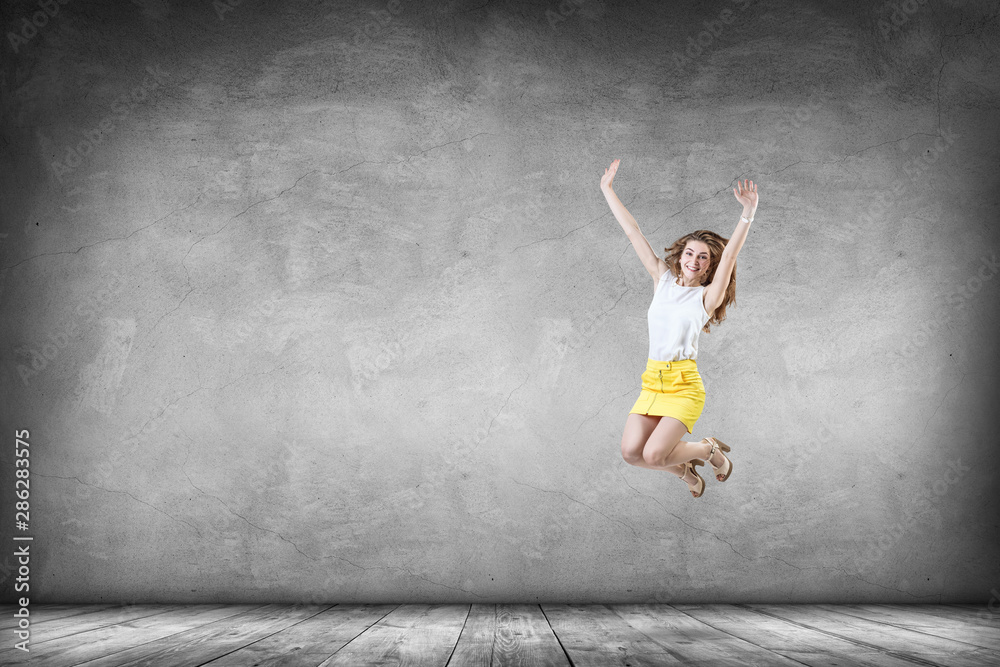 Happy young woman in yellow skirt jumps up.