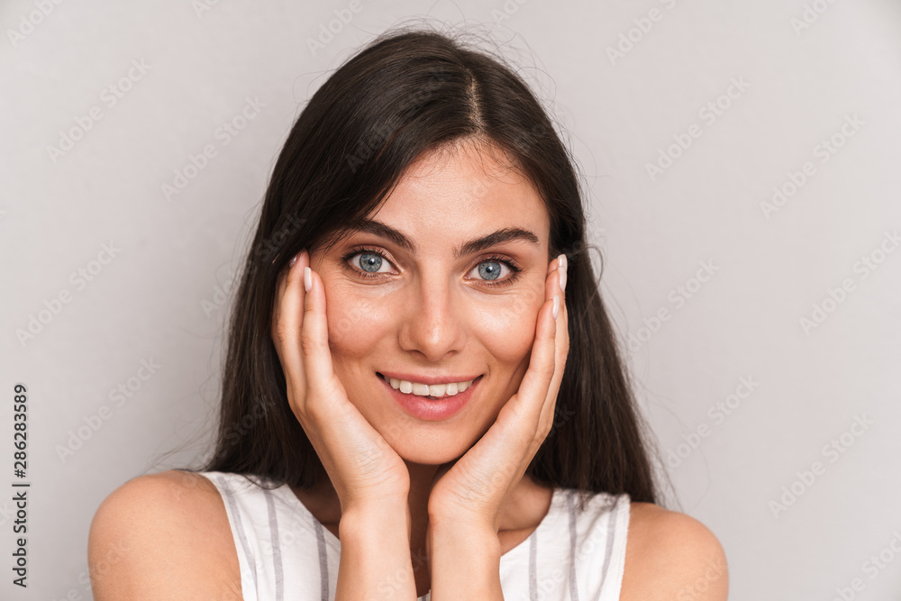Image closeup of beautiful woman with long dark hair smiling and touching her cheeks Image closeup of beautiful woman with long dark hair smiling and touching her cheeks