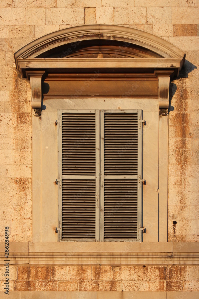 Baroque window with closed shutters at Palazzo Toscanelli in Pisa, Italy