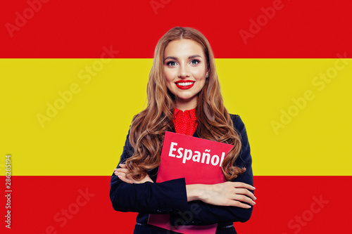 Spain. Happy student girl with red book against the spanish flag