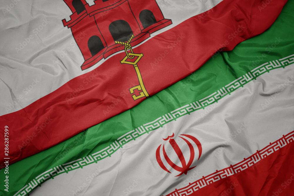waving colorful flag of iran and national flag of gibraltar.