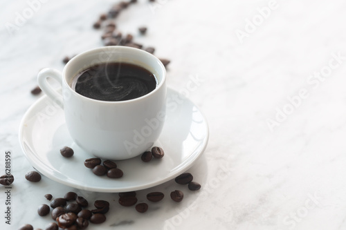 Hot cup of espresso or americano coffee in a traditional white cup on a table