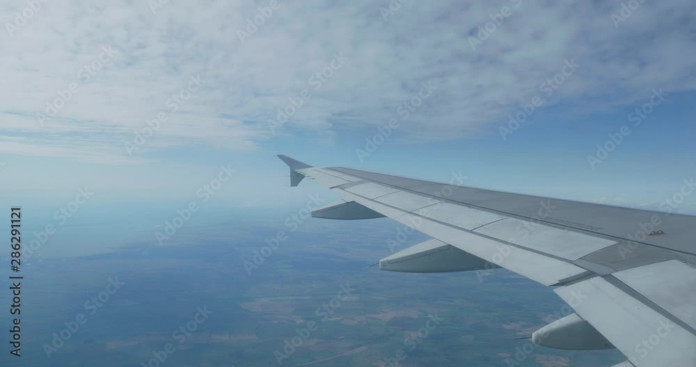 View on blue sky and fluffy white clouds through the window of the aircraft. Scenic view from flying airplane. View on blue sky and fluffy white clouds through the window of the aircraft. Scenic view from flying airplane.