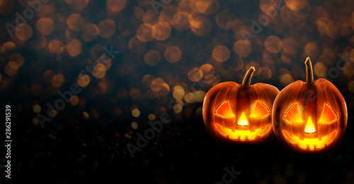 Halloween background wallpaper with jack o lantern scary pumpkins on bokeh candle light.
